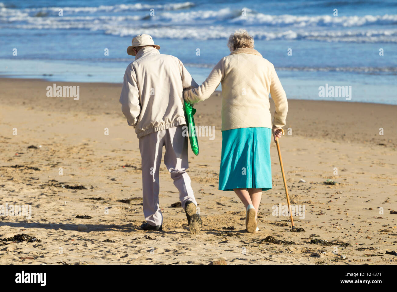 Elderly couple walking on beach. UK Stock Photo