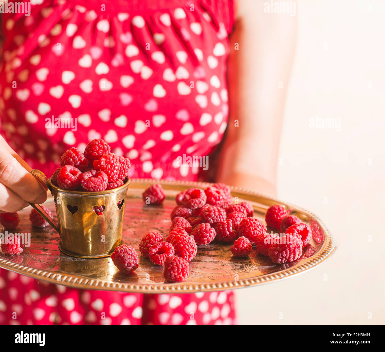 Woman in red dress holding a cup of raspberries Stock Photo - Alamy