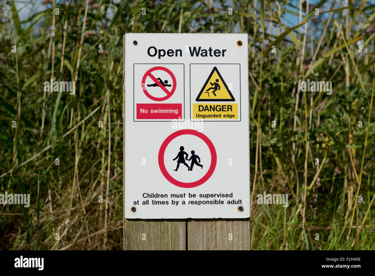 A warning sign reading Open Water by some reeds and rushes near to a beach near to Prestayn in Wales. Stock Photo