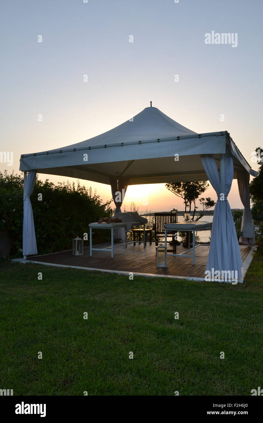 Woman lying down on massage table in outdoor spa at Cyprus, at sunset