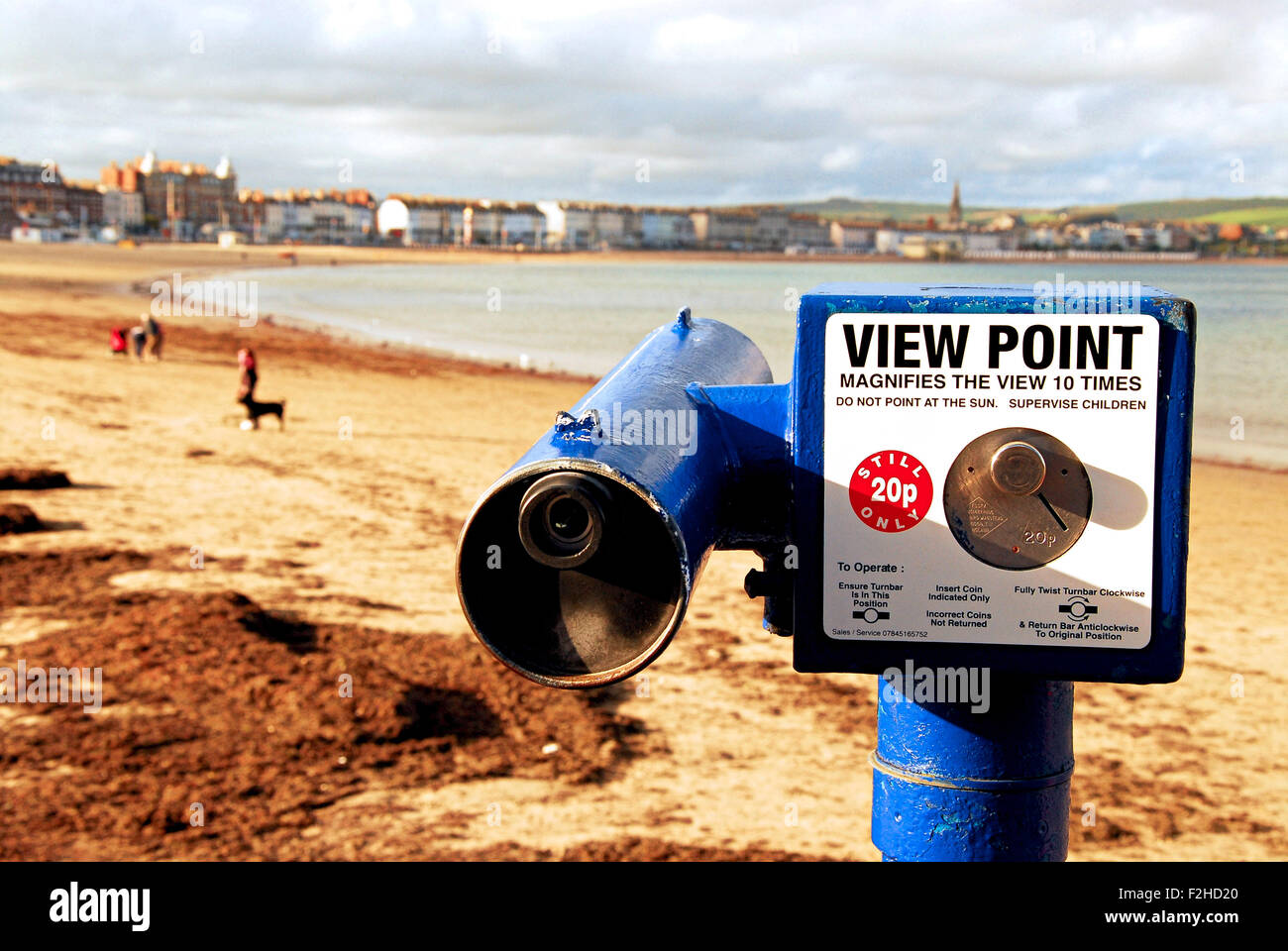 A tourist telescope points across Weymouth Bay as people enjoy the last