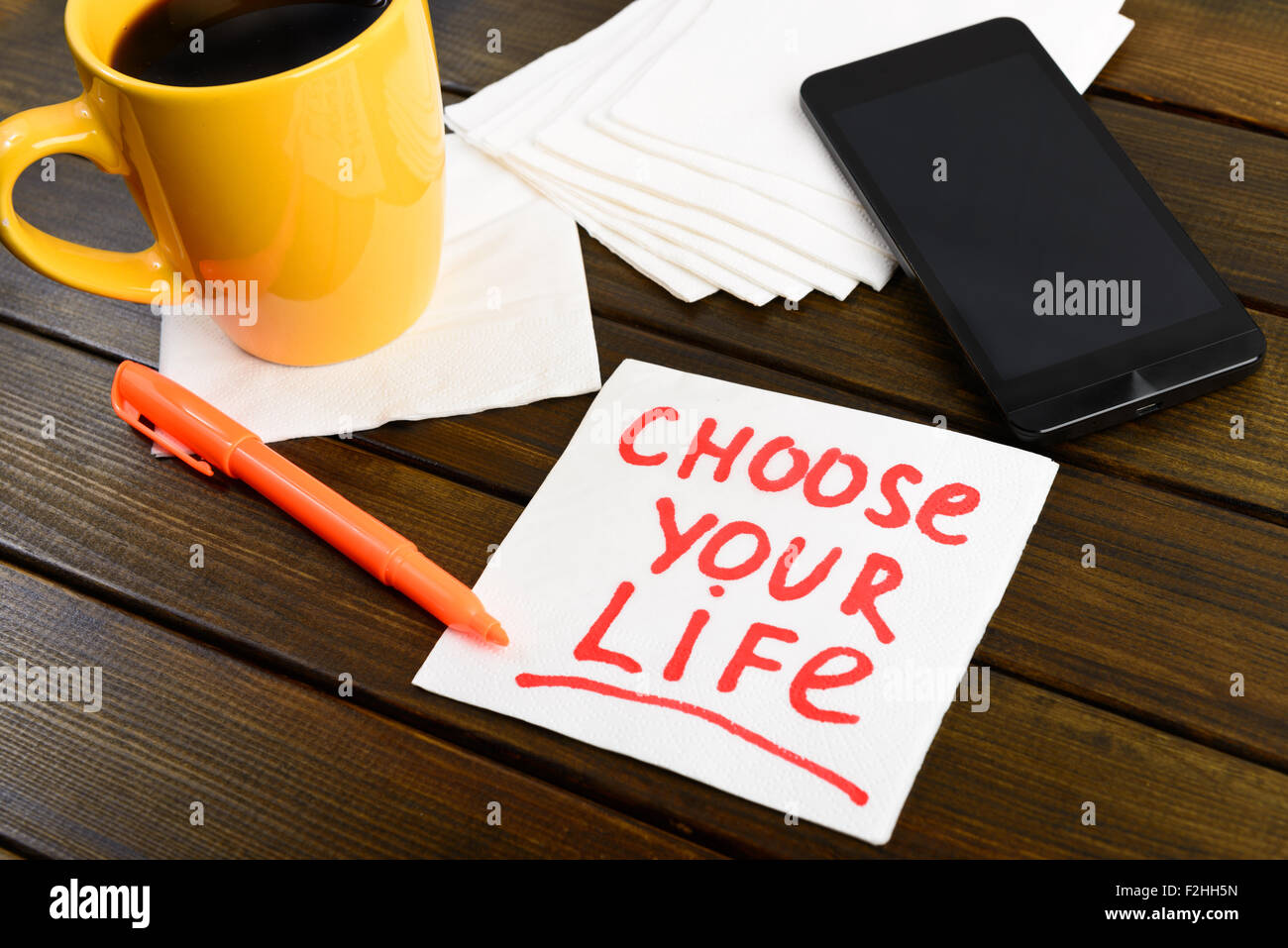 Choose your life writing on white napkin around coffee pen and phone on wooden table Stock Photo