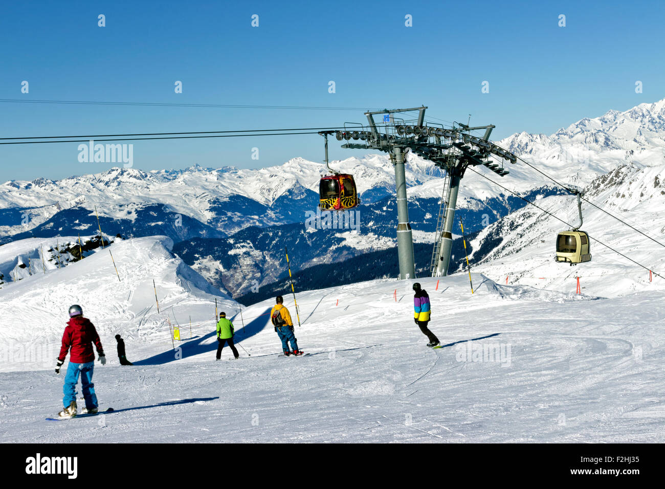 Skiing and snowboarding in high mountains, with ski cable lift in the background Stock Photo