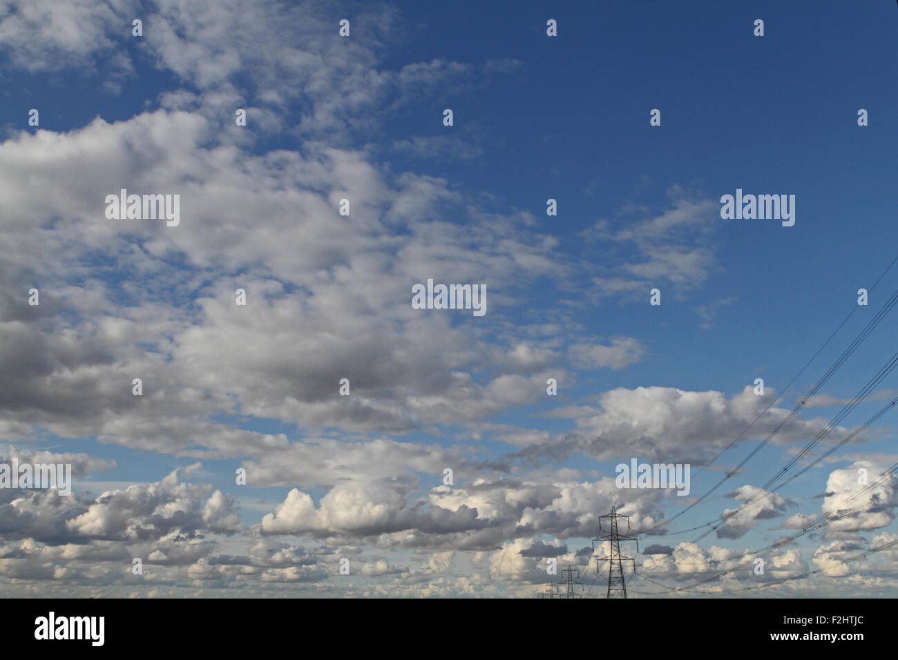 Electricity pylons against a cloudy blue sky Stock Photo