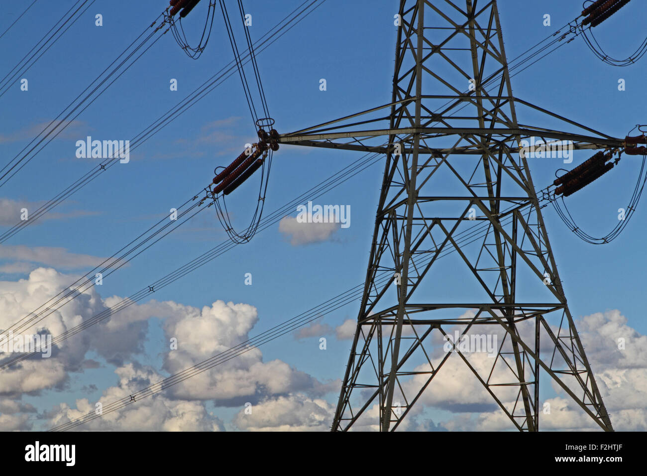 Electricity pylons against a cloudy blue sky Stock Photo - Alamy