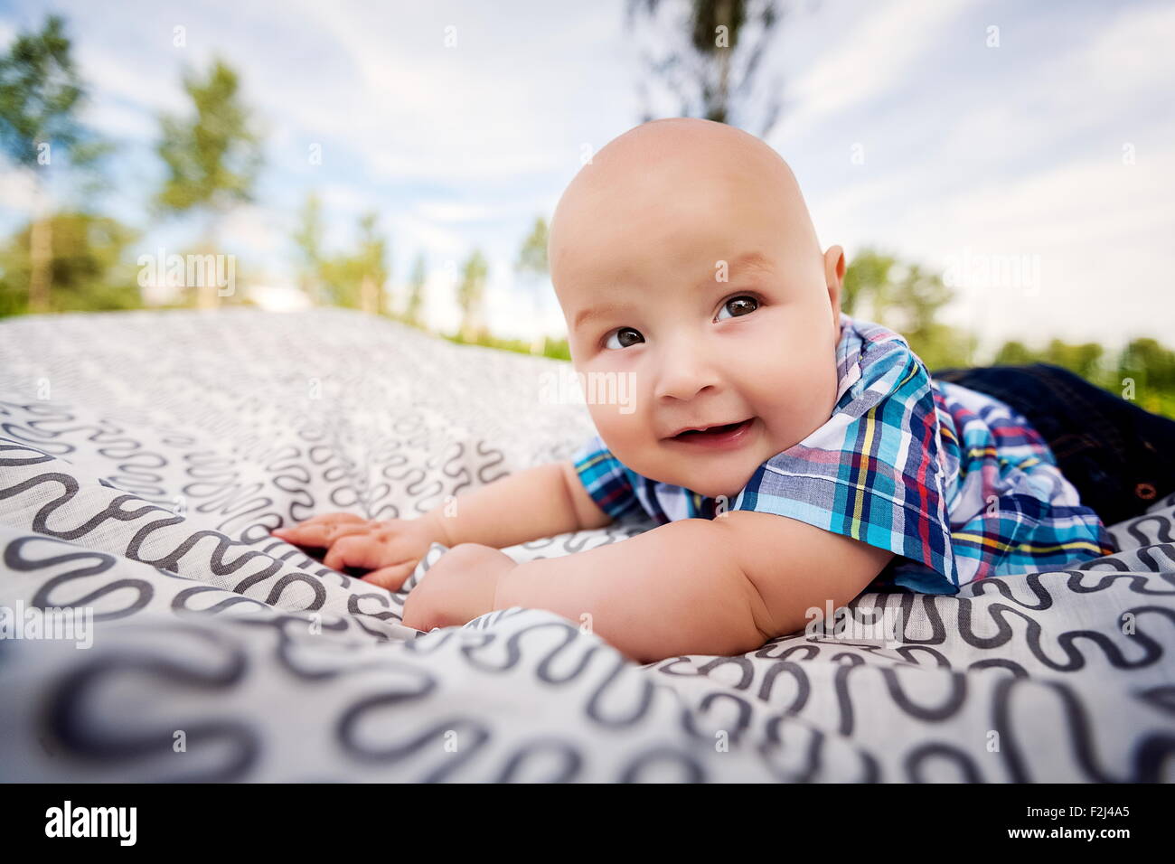 little boy in plaid shirt lying on blankets. Stock Photo