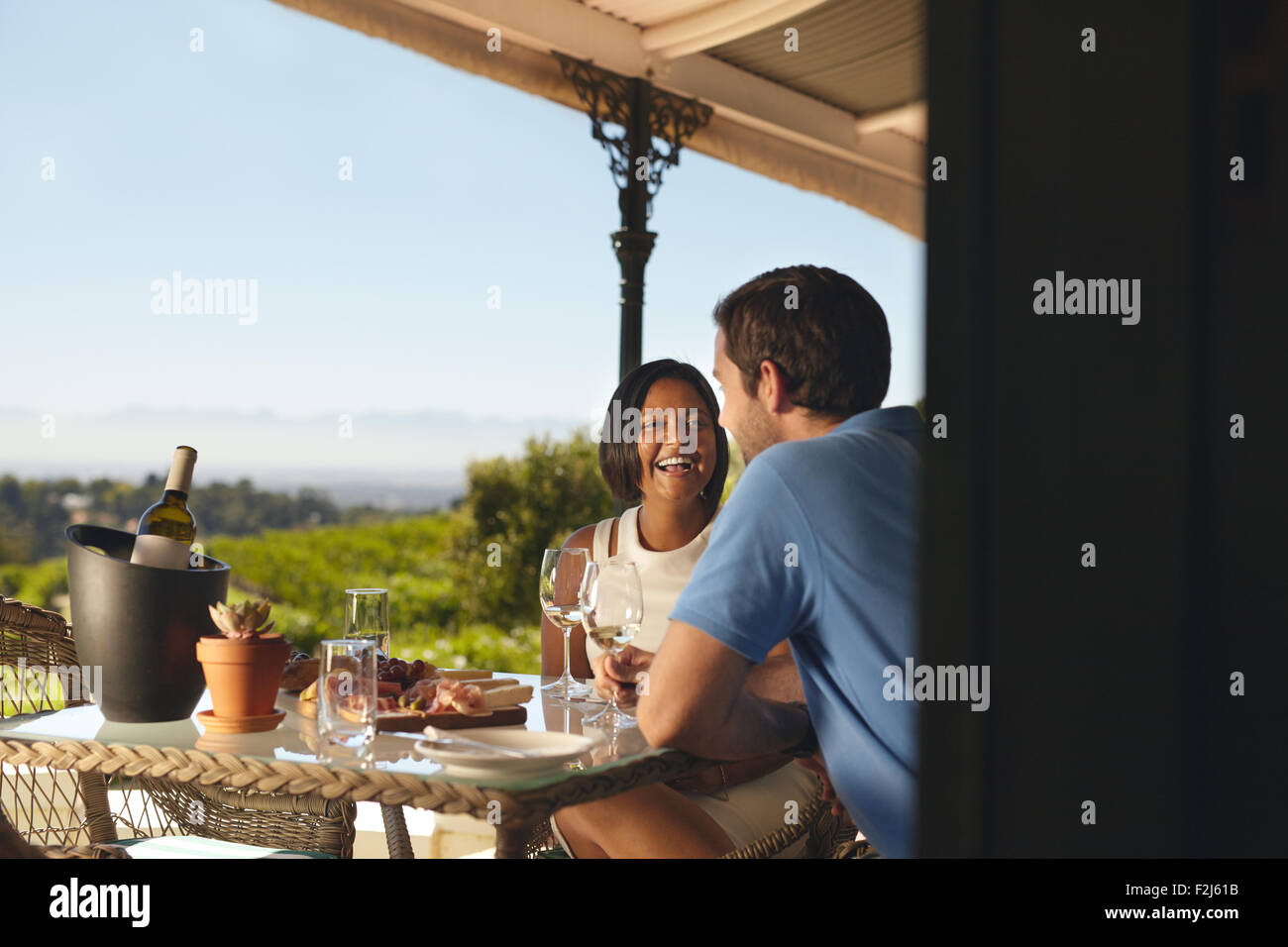 Young couple on vacation drinking wine in a restaurant in countryside. Smiling young woman with her boyfriend in a winery restau Stock Photo