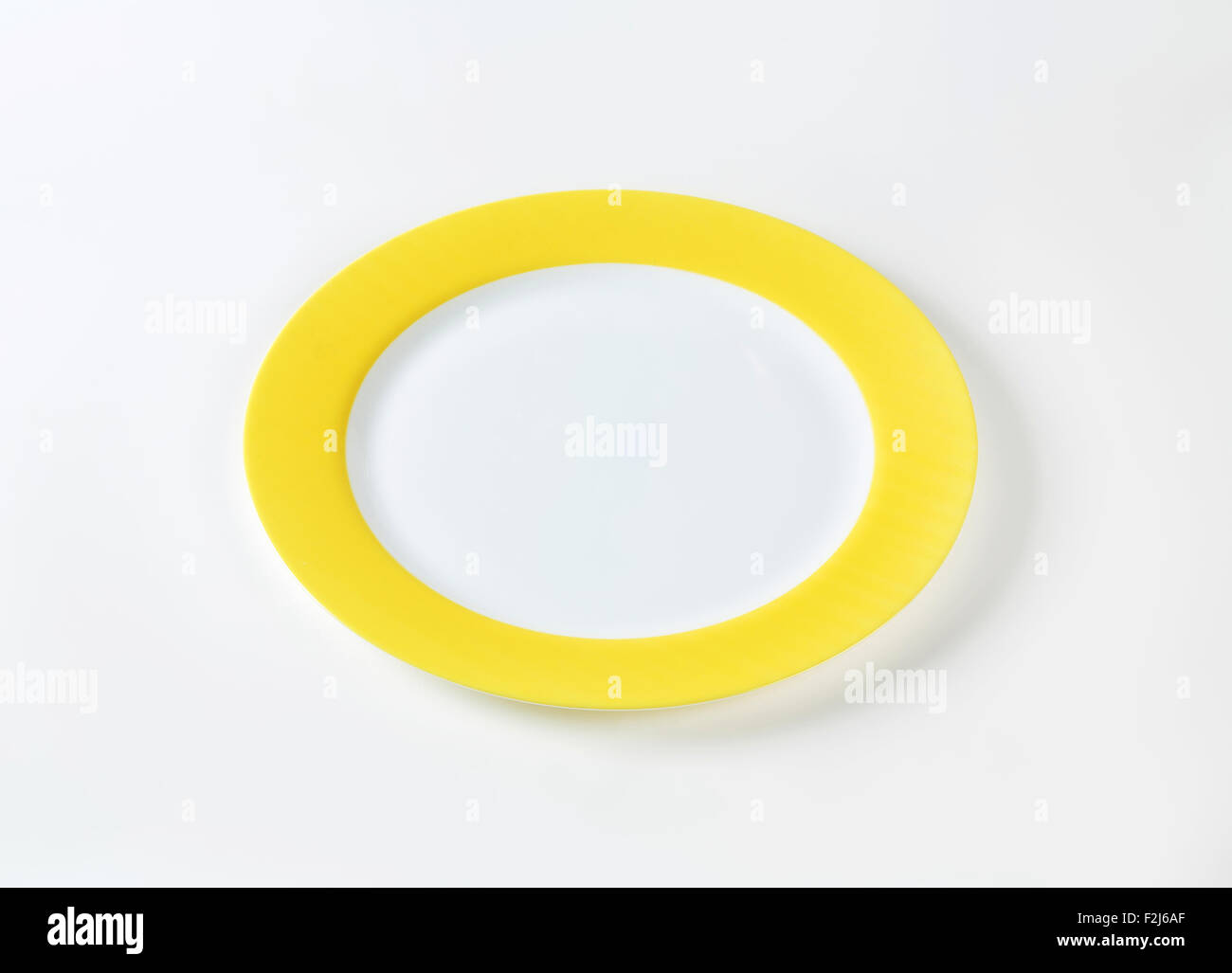 white plate with yellow rim on white background Stock Photo