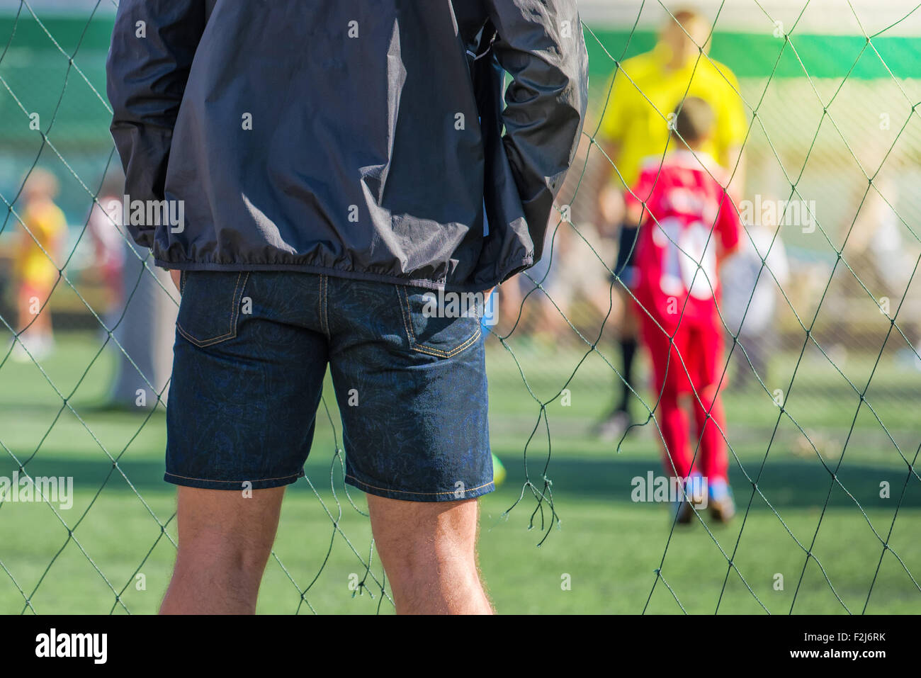 Father watching son playing soccer game, kids playing football, selective focus Stock Photo