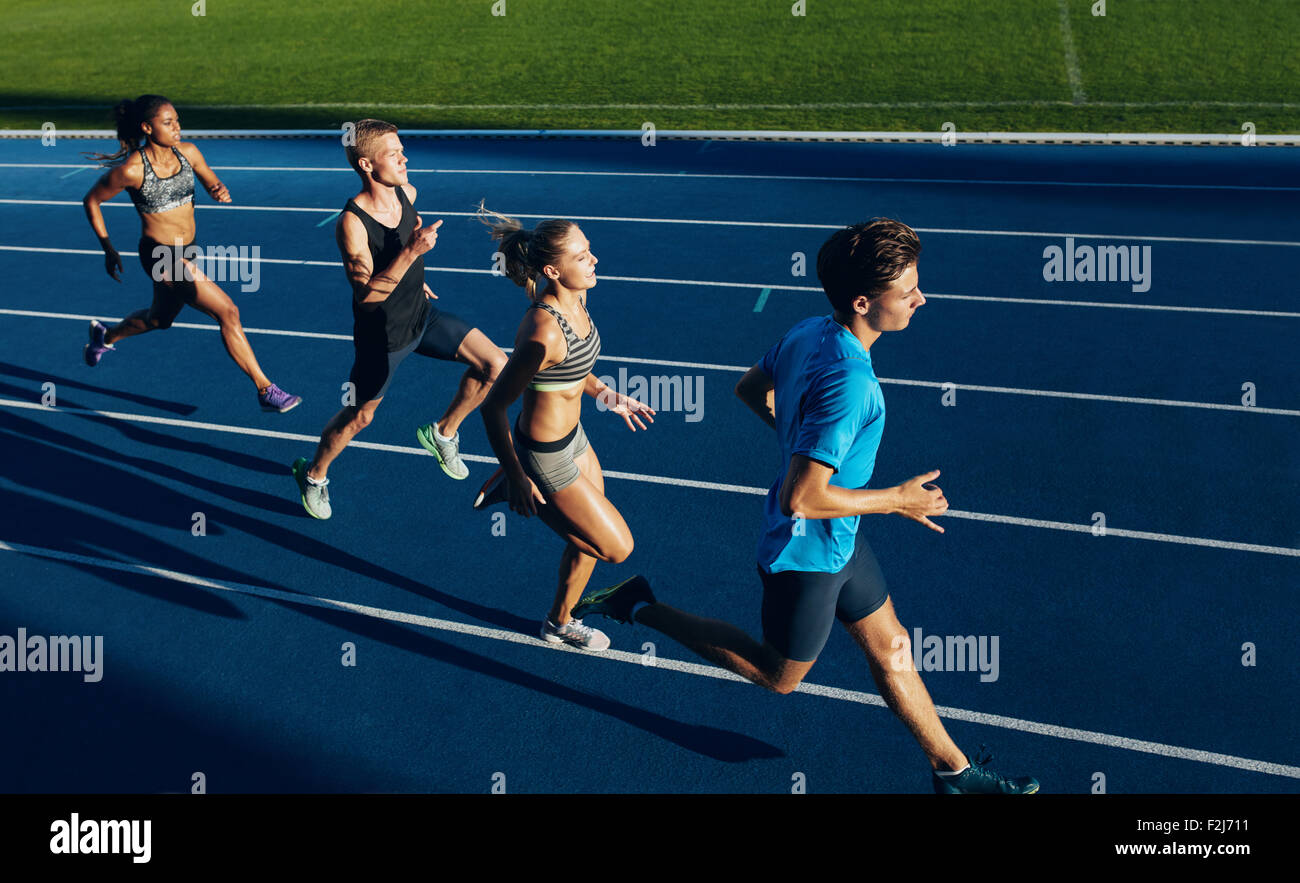 Group of multiracial athletes practicing running on racetrack. Male and female athletes during running session at athletics stad Stock Photo