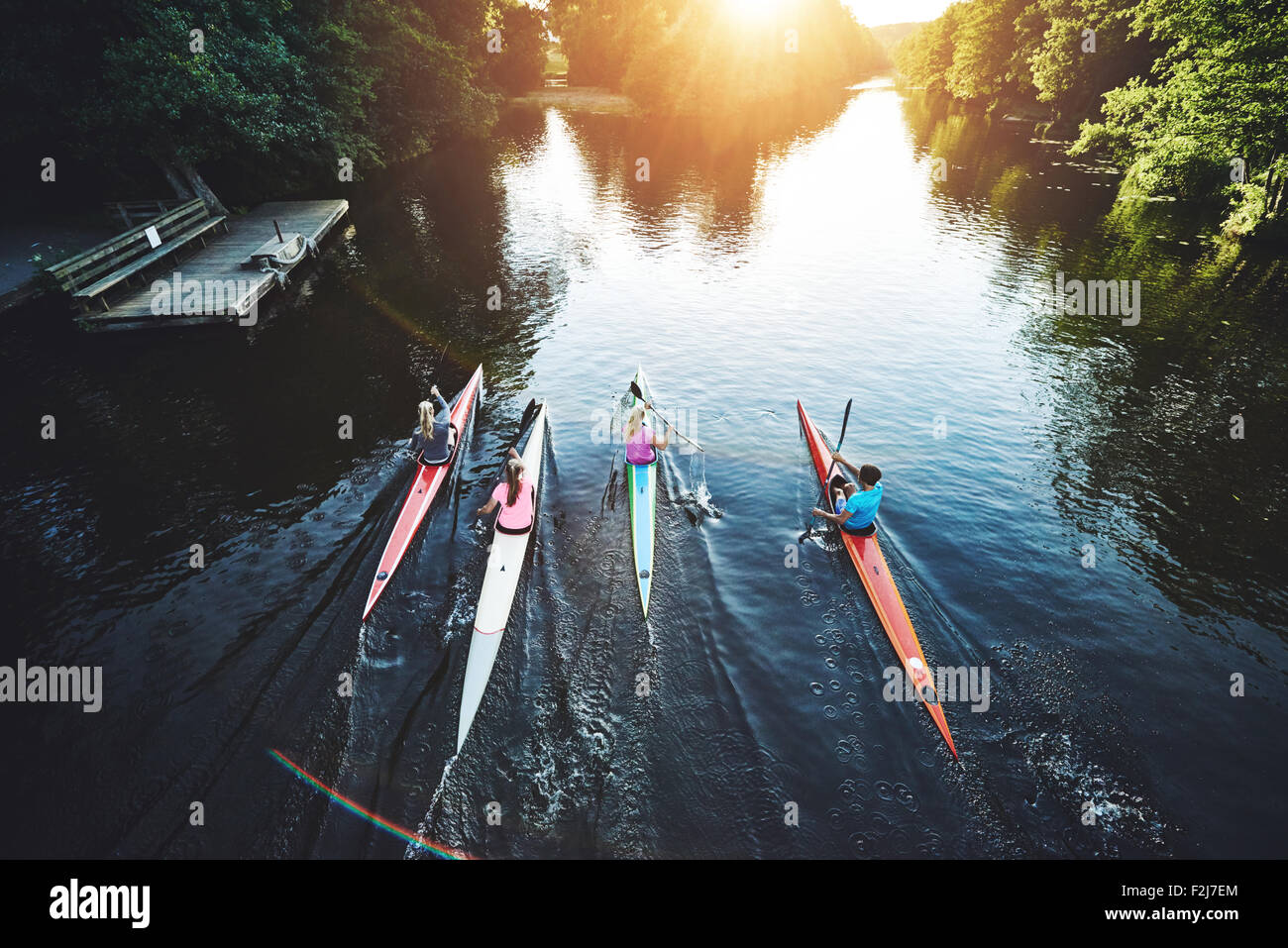 Team of rowing people racing in the sunset Stock Photo