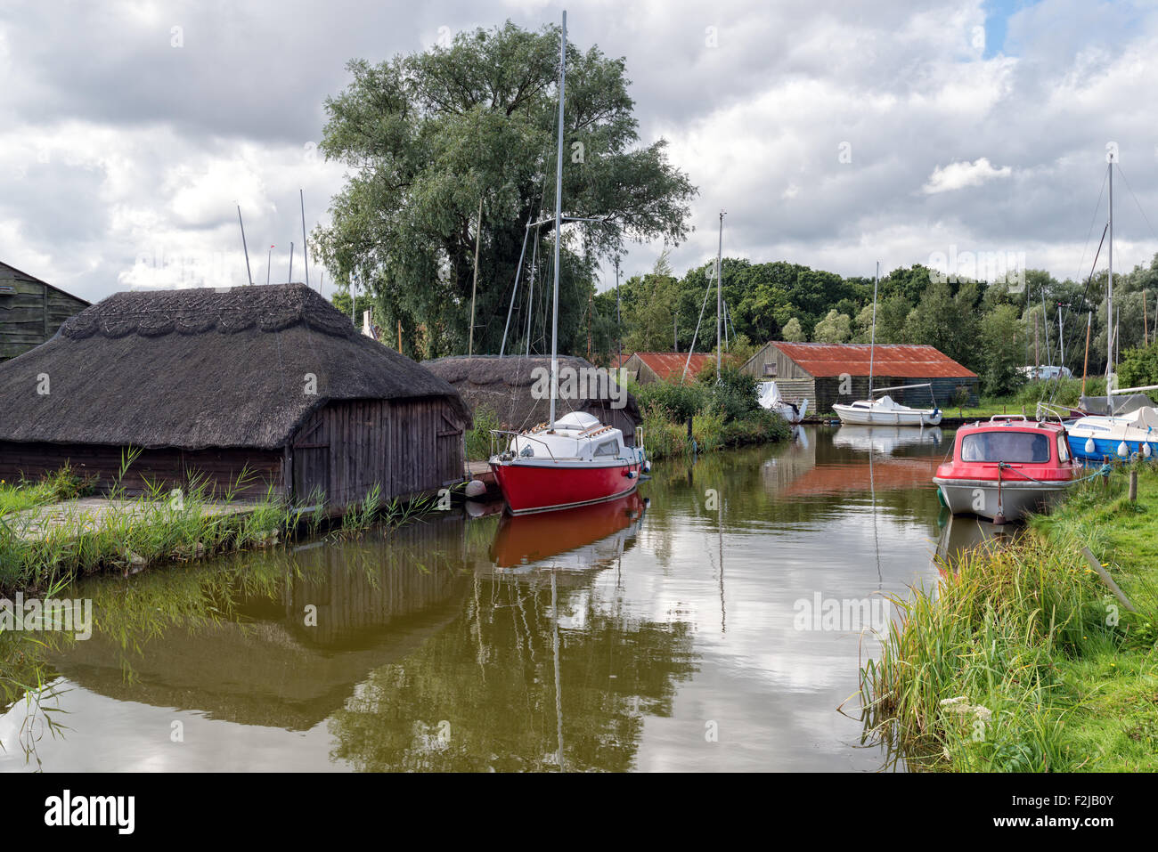 Boats and thatched boat houses on Hickling Broad in Norfolk Stock Photo