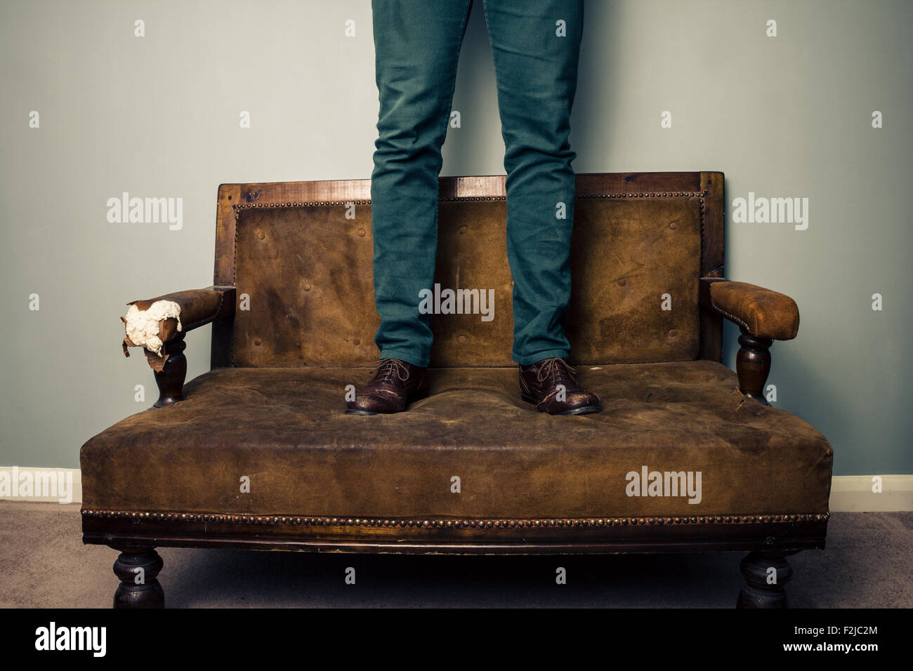Legs of man standing on a sofa Stock Photo