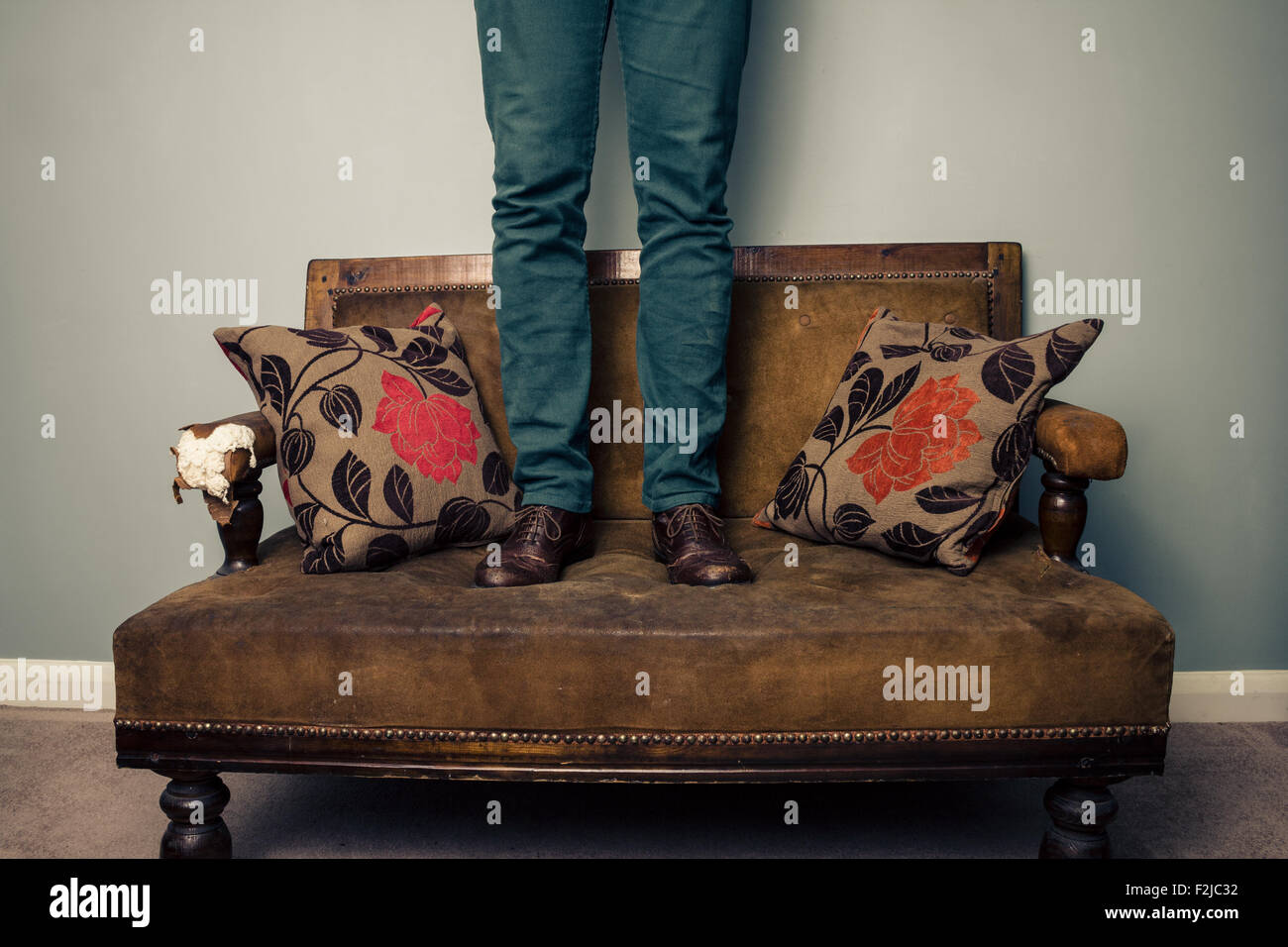 Legs of man standing on sofa Stock Photo