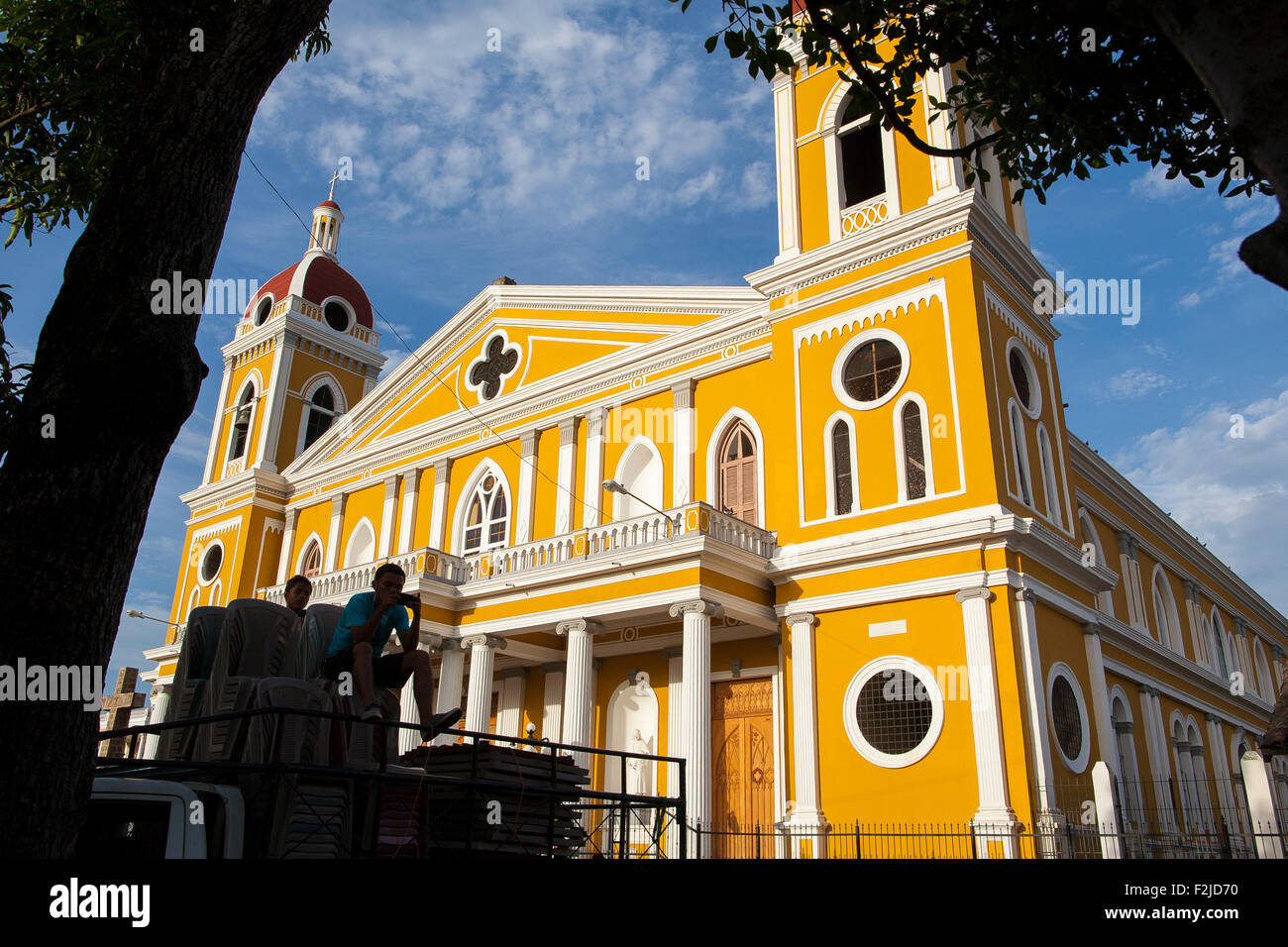 A boy is silhouetted against the famous and colorful cathedral of Granada on the main plaza or square in Grenada Nicaragua Stock Photo