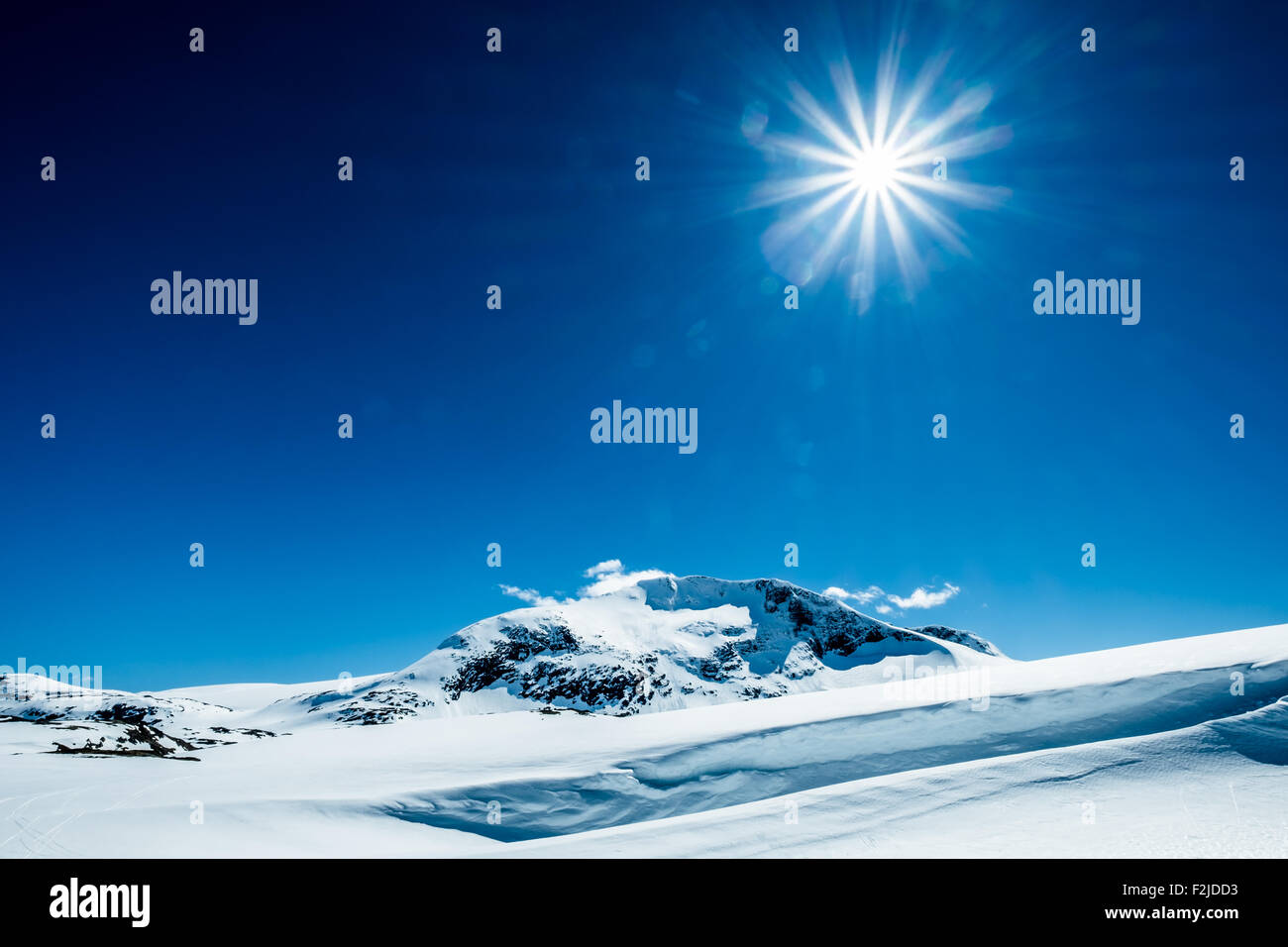 Sun in a blue sky over snowy mountain. Stock Photo