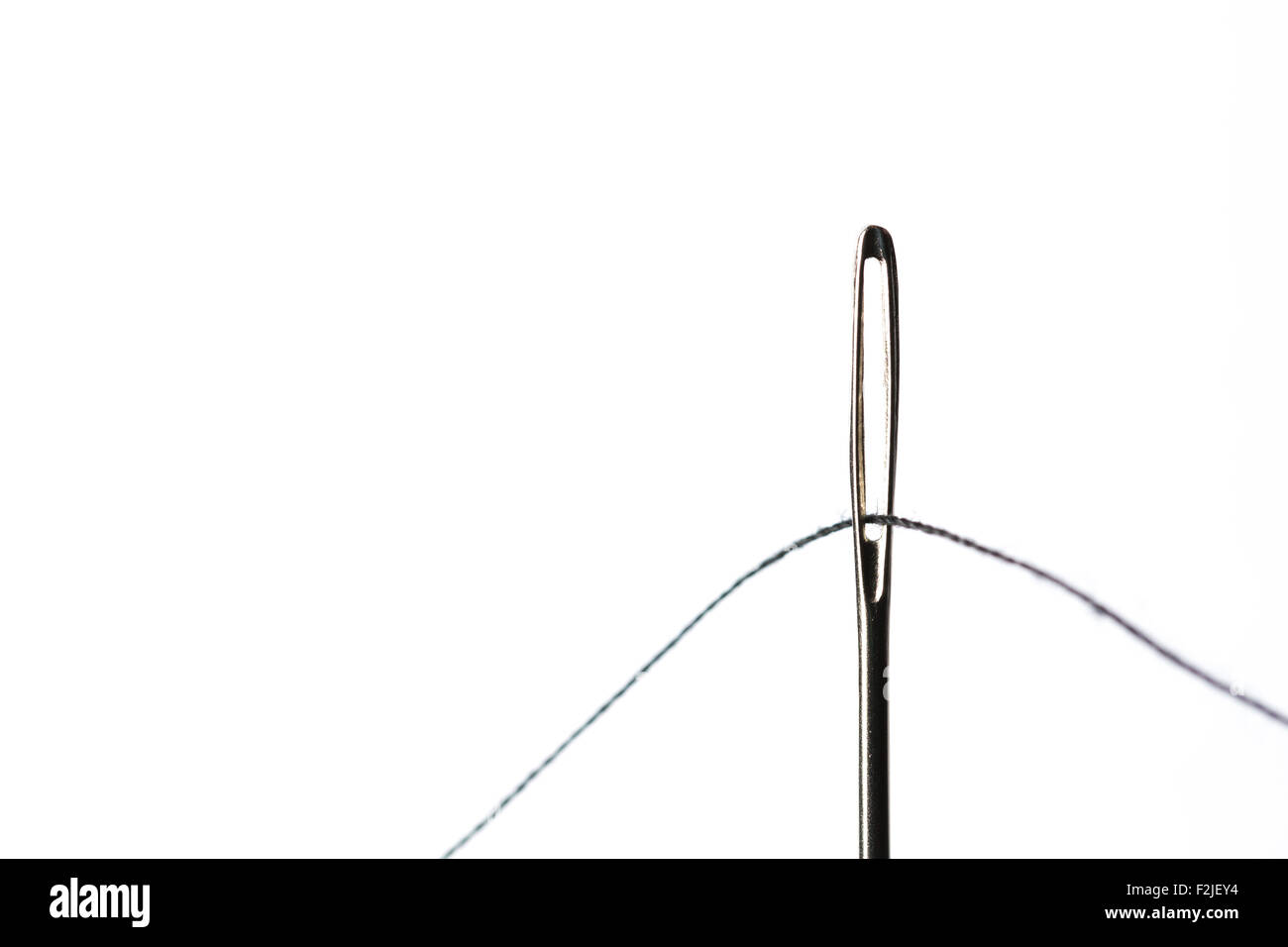 Sewing Needle Close Up With Black Thread through the eye Stock Photo