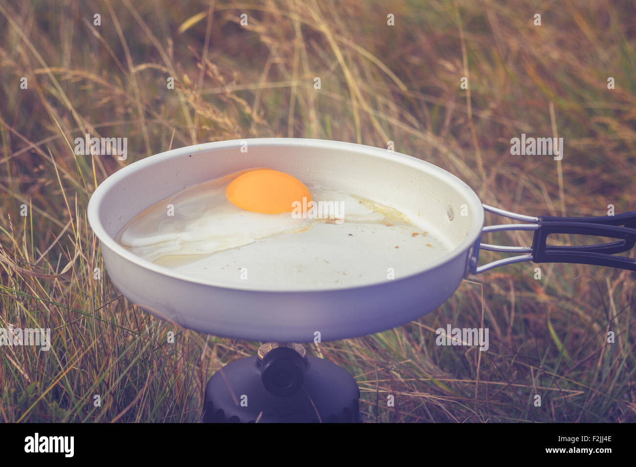 Egg frying on camping stove in nature Stock Photo