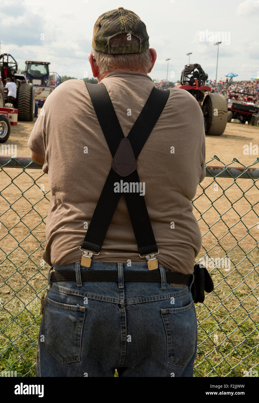 A man wearing suspenders and jeans watching the tractor pulling event at the Washington County Fair in Greenwich, New York State Stock Photo