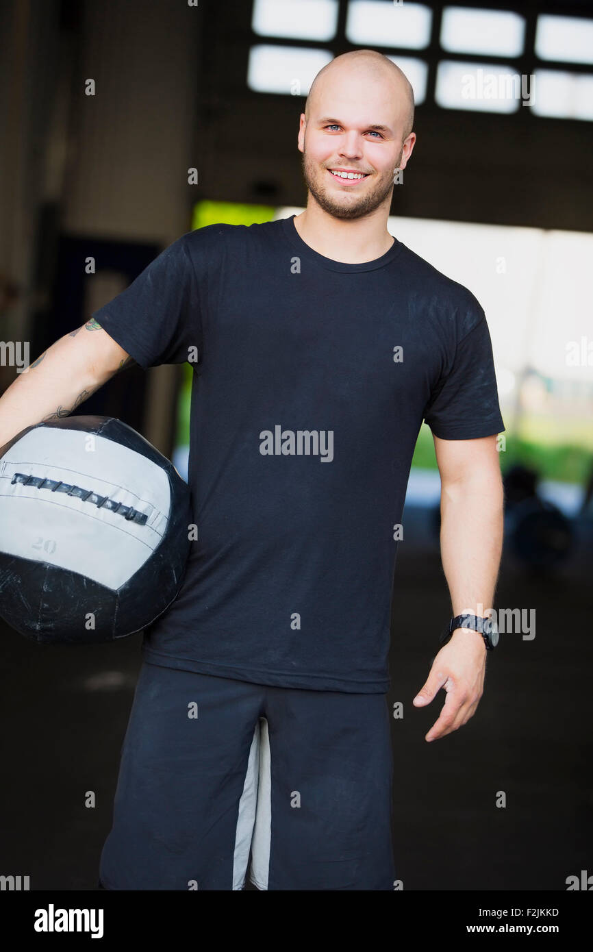 Smiling young man with med-ball at the fitness gym Stock Photo