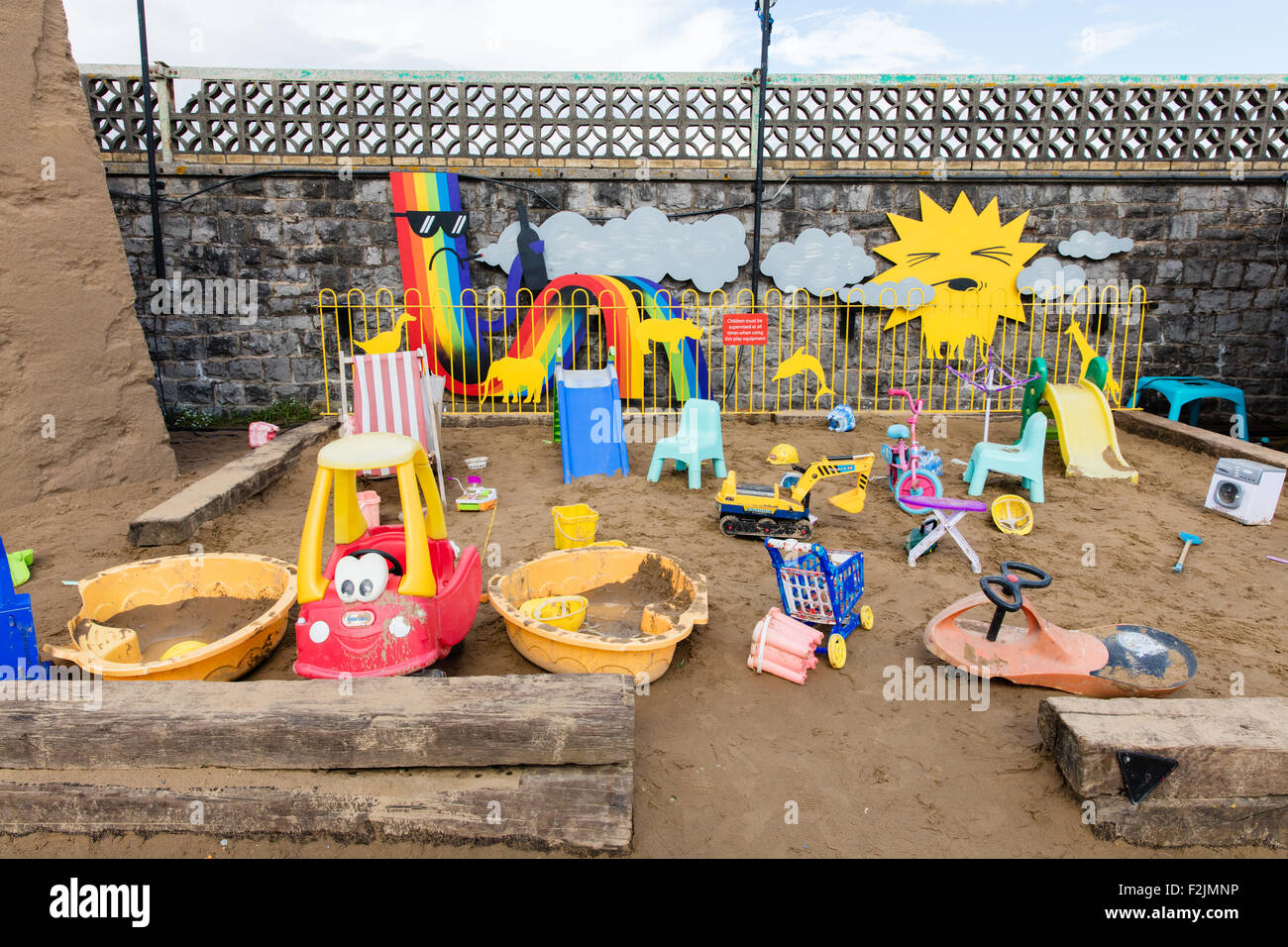 Kids sandpit corner at Banksy's Dismaland in Weston super Mare UK with a selection of rundown children's toys and playthings Stock Photo