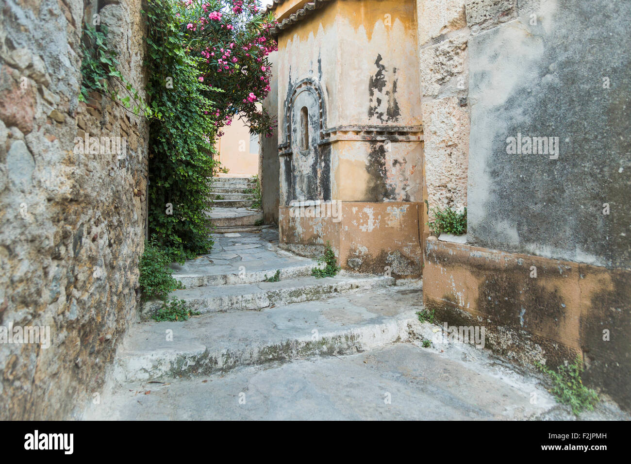 Old stone pathway with bougainvillea growing on side of buidling in Plaka Athens Greece Stock Photo