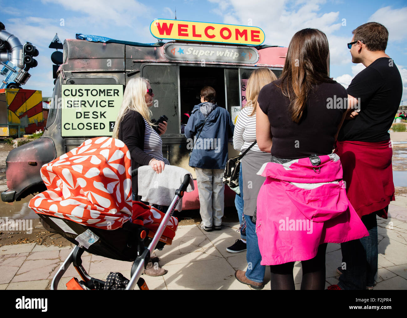People queuing at the customer service desk ( closed 24 hours ) in a burned out ice cream van at