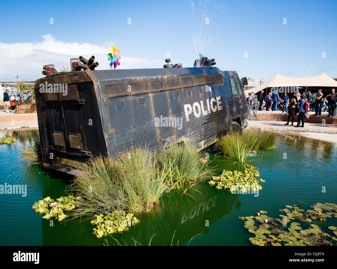 Livid green polluted pond and armour plated police riot vehicle fountain at Banksy's Dismaland in Weston super Mare UK Stock Photo