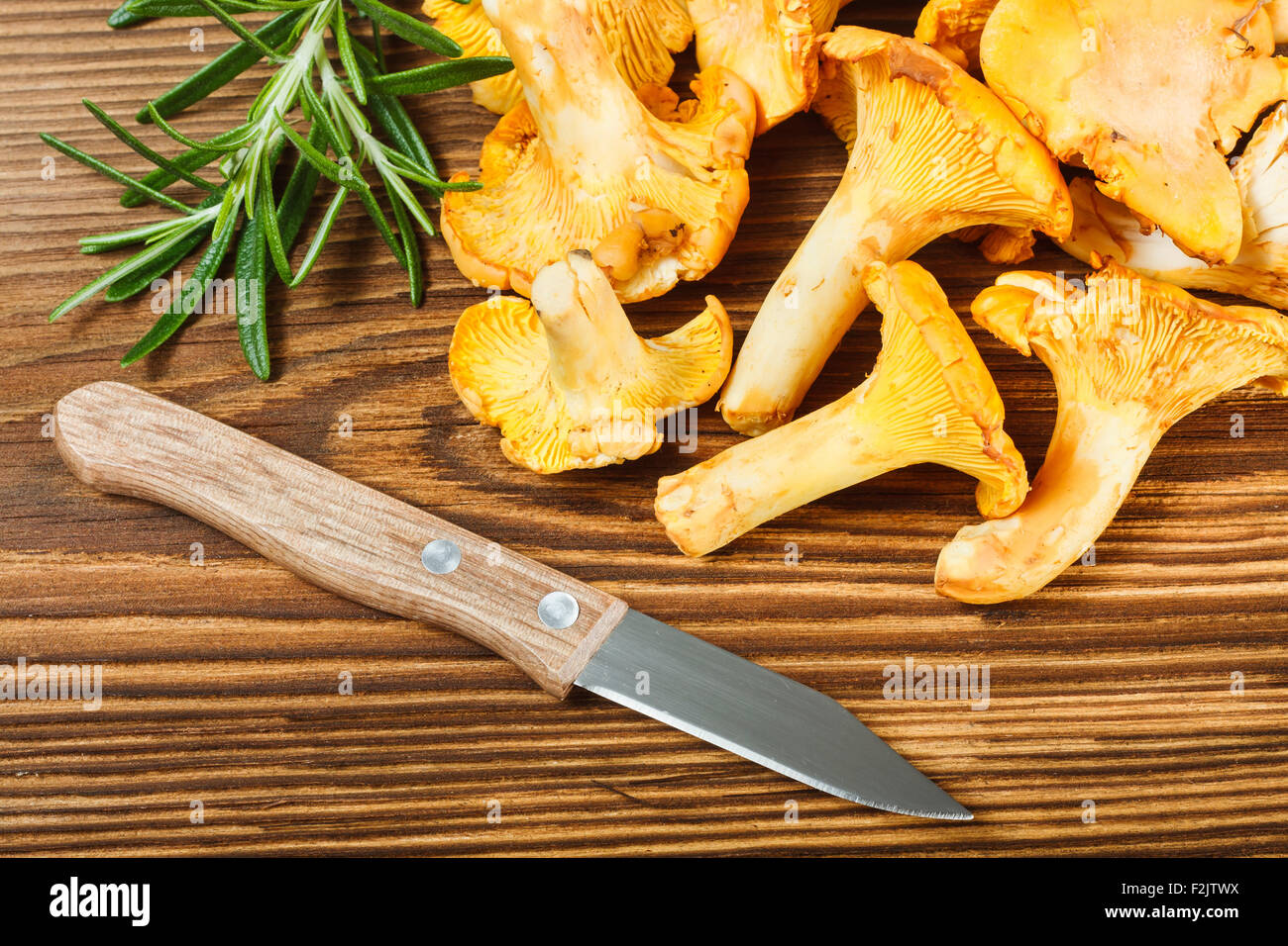 Yellow chanterelles and knife on wooden table Stock Photo