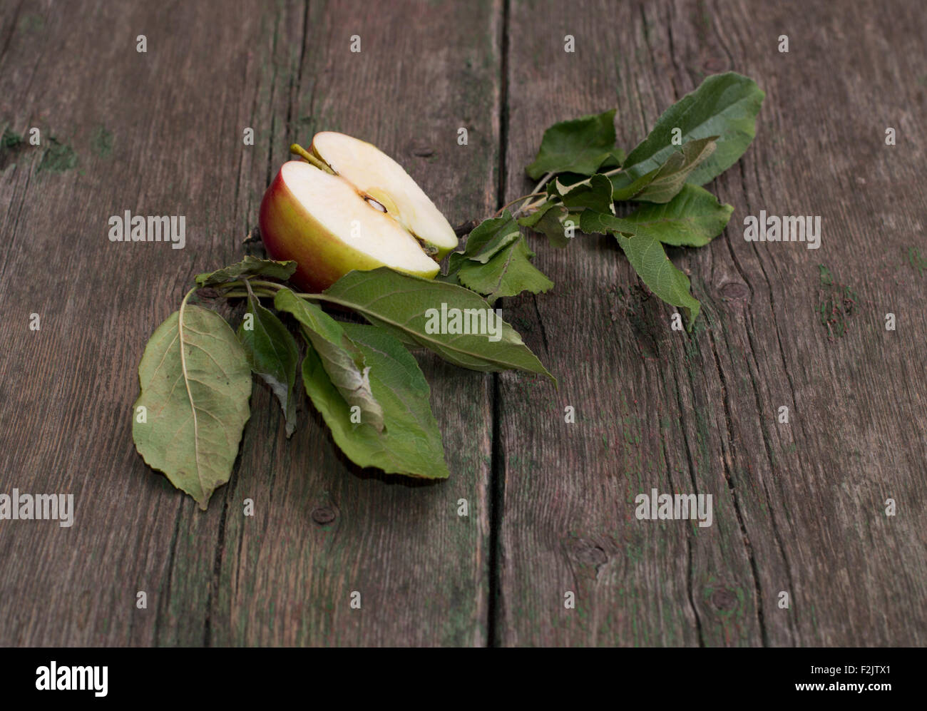 the cut apple with leaves on an old wooden table Stock Photo