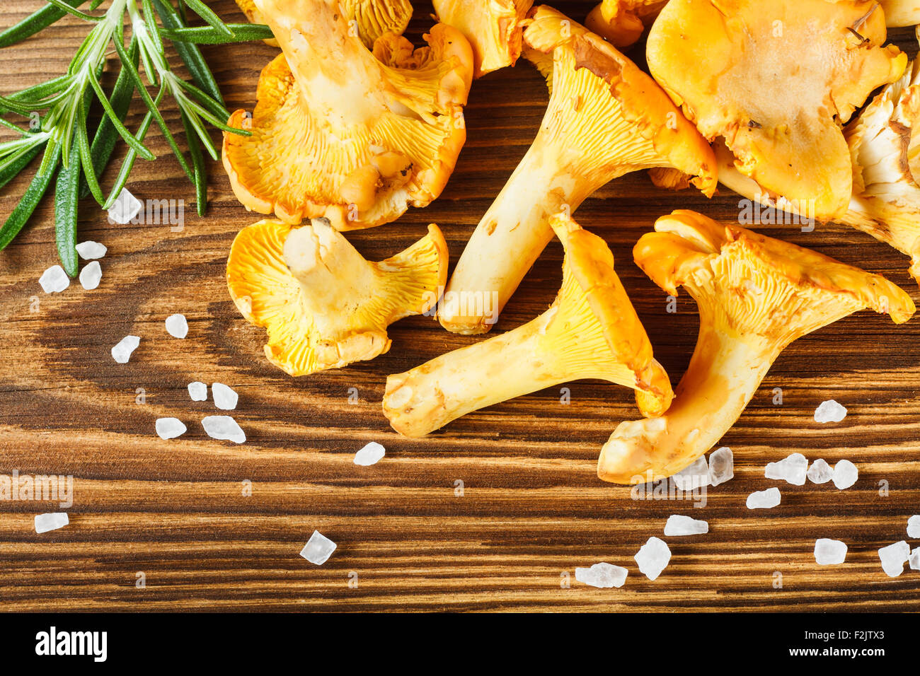 Yellow chanterelles and salt crystals on wooden table Stock Photo