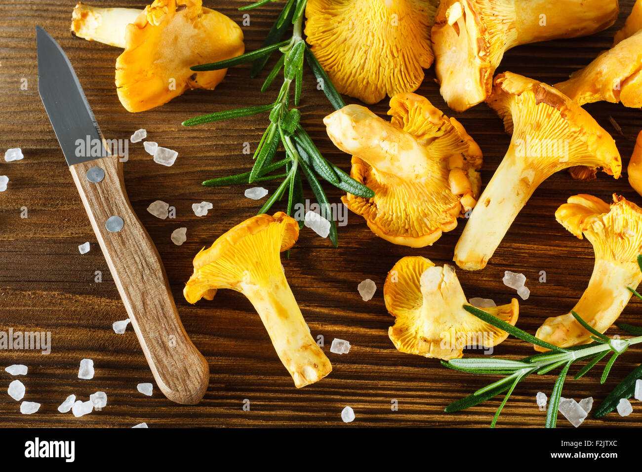 Yellow chanterelles, knife and salt crystals on wooden table Stock Photo