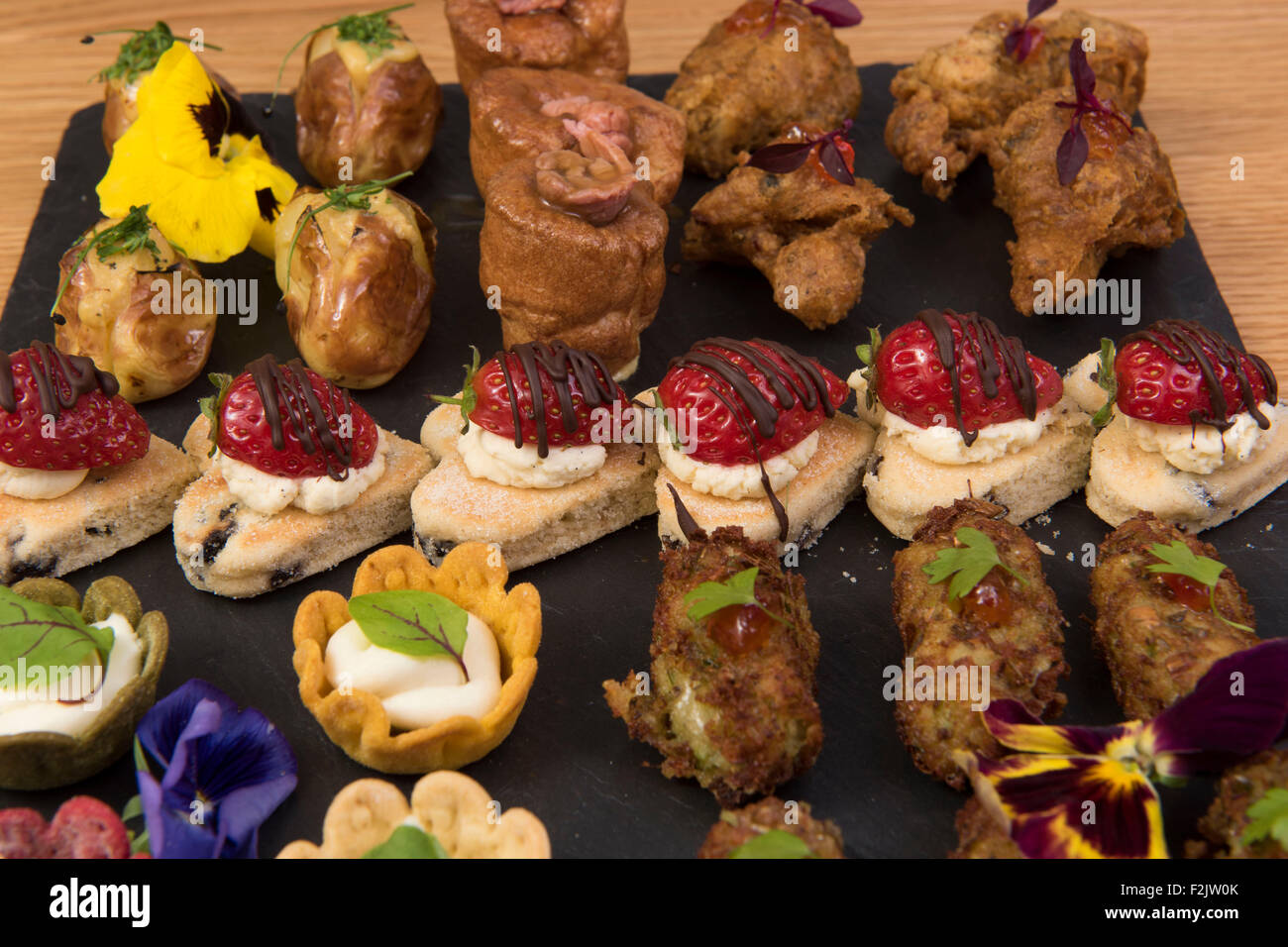 A selection of canapes and appetizers on a dark slate plate. Stock Photo