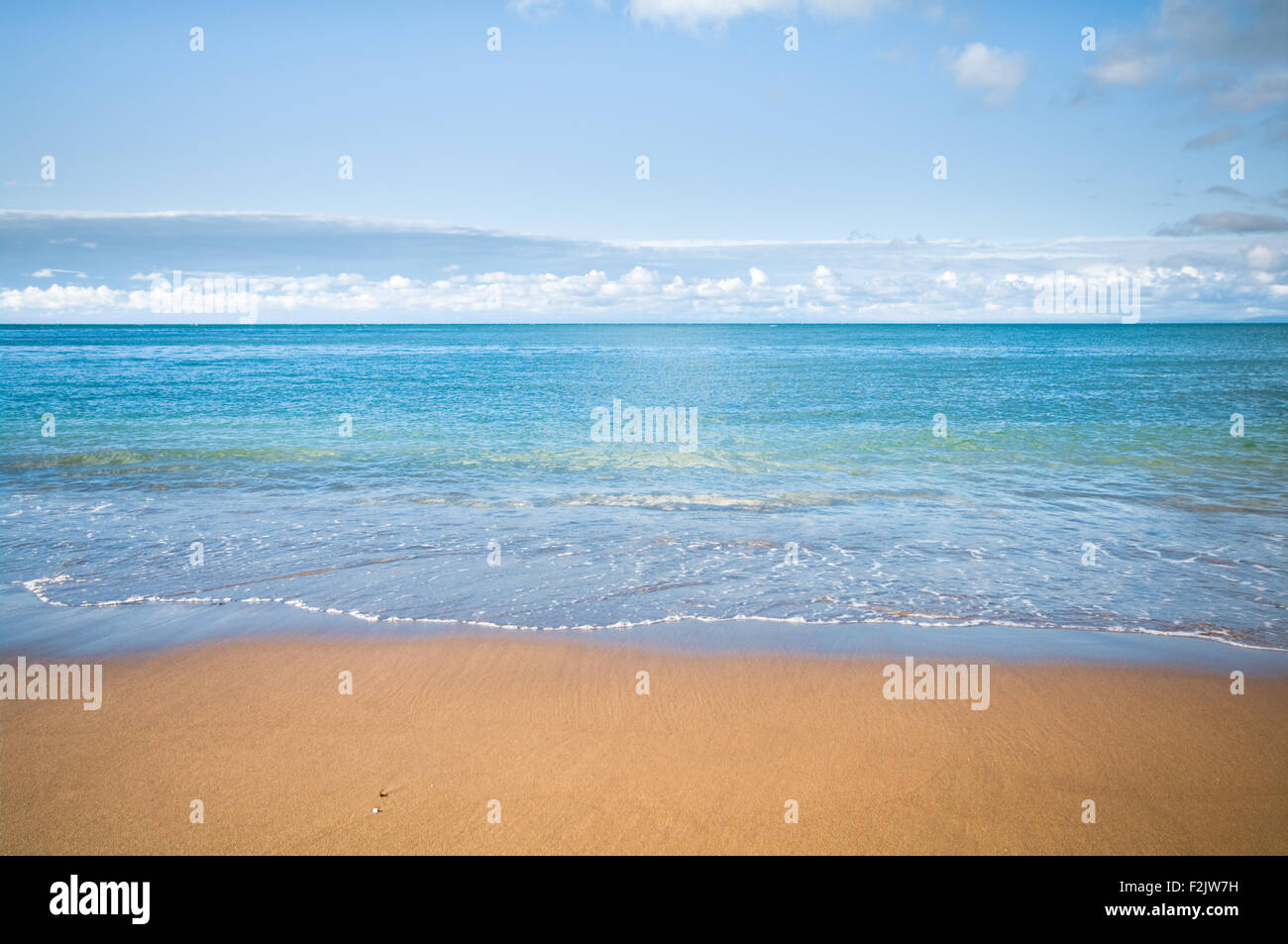 A coastal beach scene with blue sky, sea and golden sand Stock Photo ...