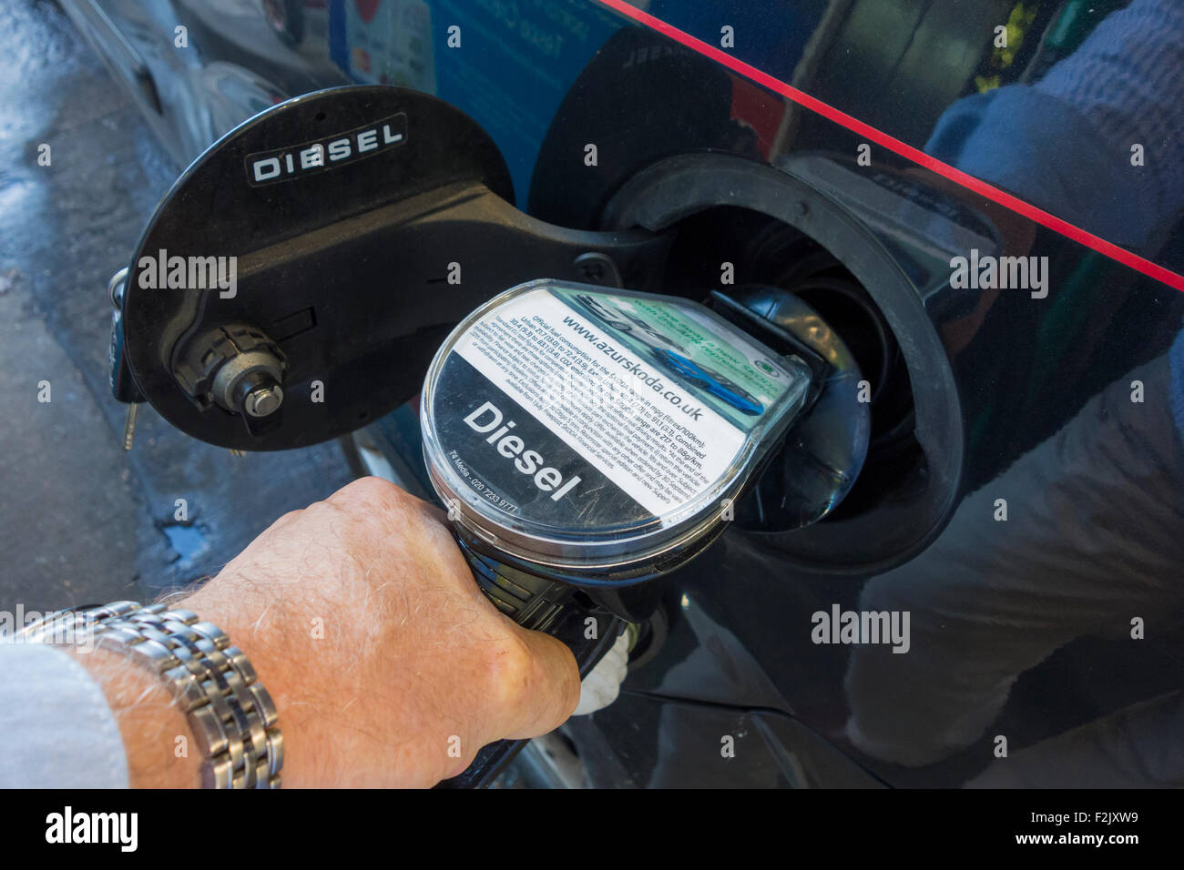 mans hand shown holding a diesel fuel pump whilst dispensing fuel into fuel tank of diesel