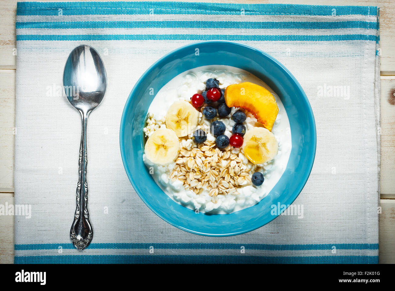 Healthy breakfast. Granulated cottage cheese plus oat flakes, banana, blueberries, red currant, peach and honey. Photo in vintag Stock Photo