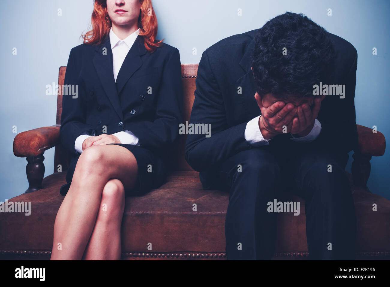 Confident businesswoman and crying businessman on sofa Stock Photo
