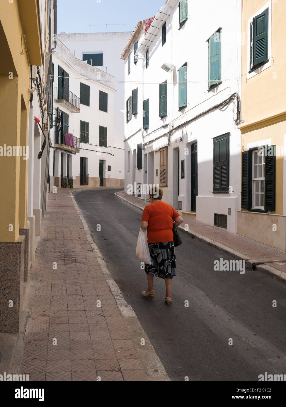 Old lady walking up traditional residential street in Mahon, Menorca Stock Photo