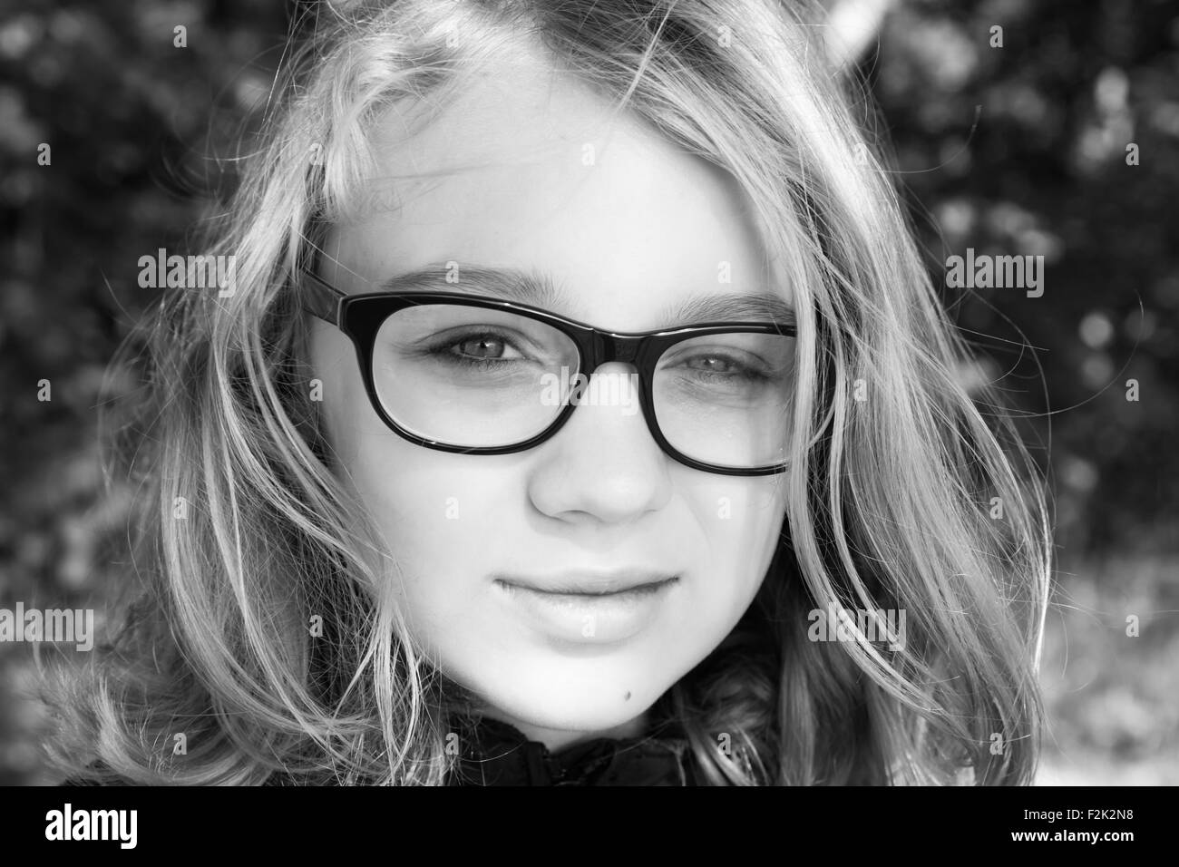 Beautiful blond Caucasian teenage girl in glasses, outdoor monochrome portrait Stock Photo