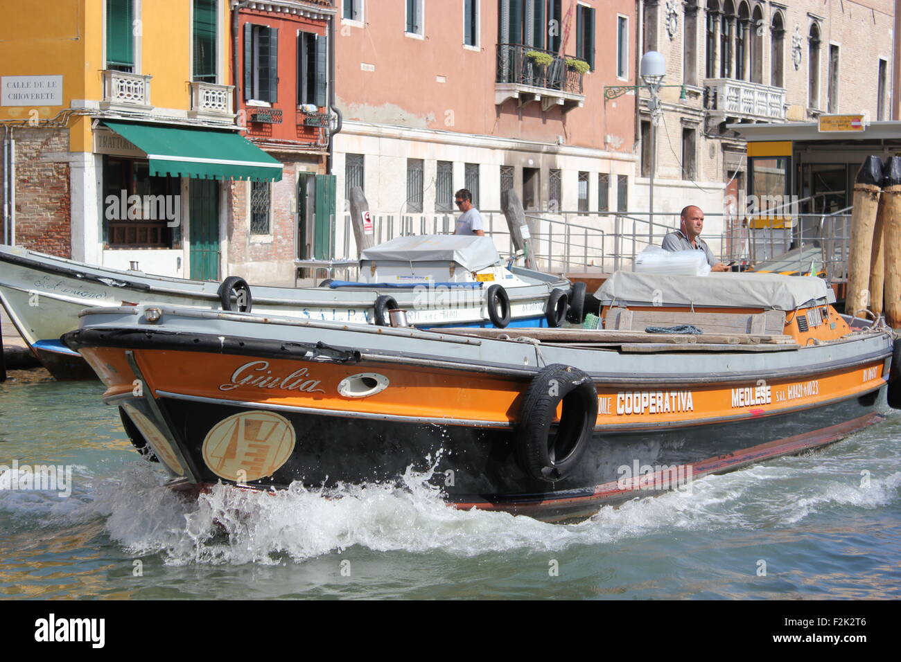 A boat speeds along a canal in Venice Italy Stock Photo