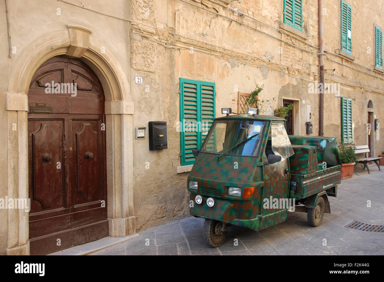 A camouflaged Piaggio Ape in one of the narrow lanes of the Tuscan hill-top town of Campiglia Marittima, Italy. Stock Photo