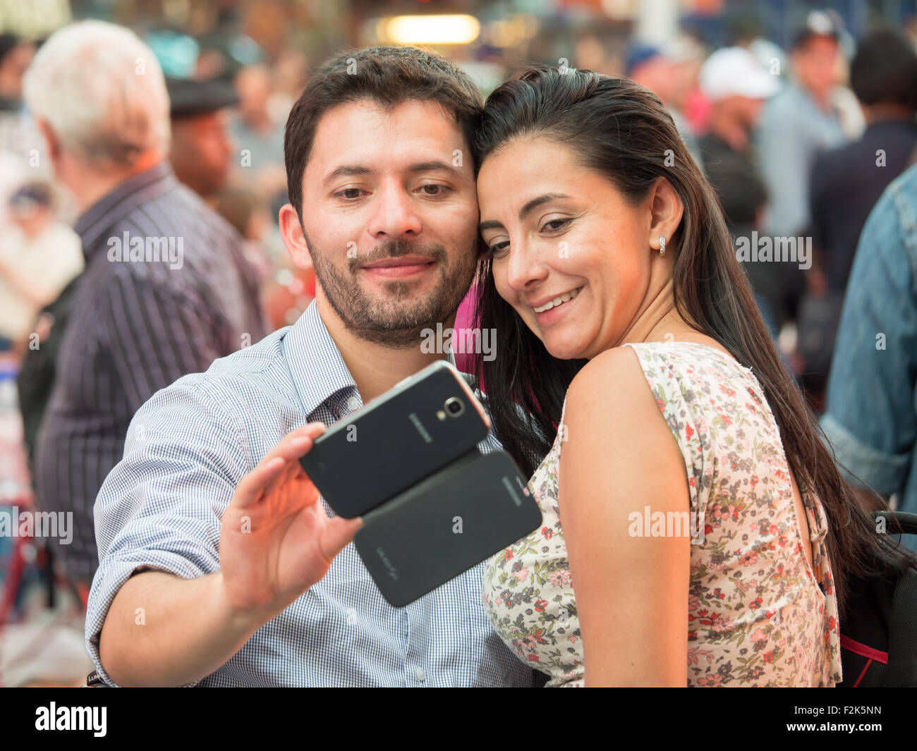 A couple takes a selfie with a smartphone while visiting Times Square in New York City. Stock Photo