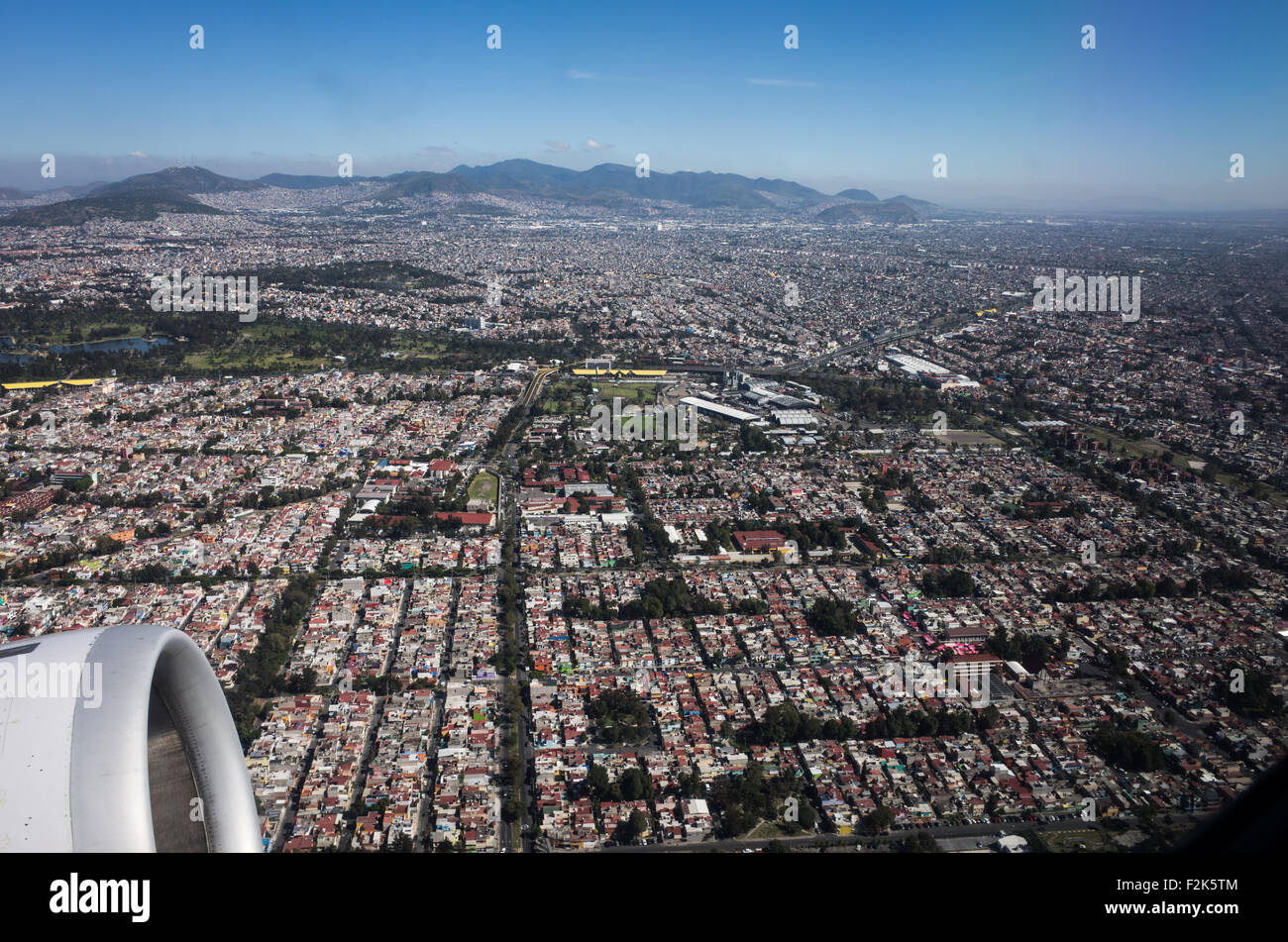 Aerial View Mexico City // An aerial view of Mexico unfolds beneath the plane, revealing a diverse tapestry of landscapes. From rugged mountain ranges and sprawling deserts to lush forests and winding coastlines, this bird's-eye perspective showcases the country's rich geographical variety. Cities and rural areas alike punctuate the terrain, offering a stunning visual representation of Mexico's natural beauty and human development. Stock Photo