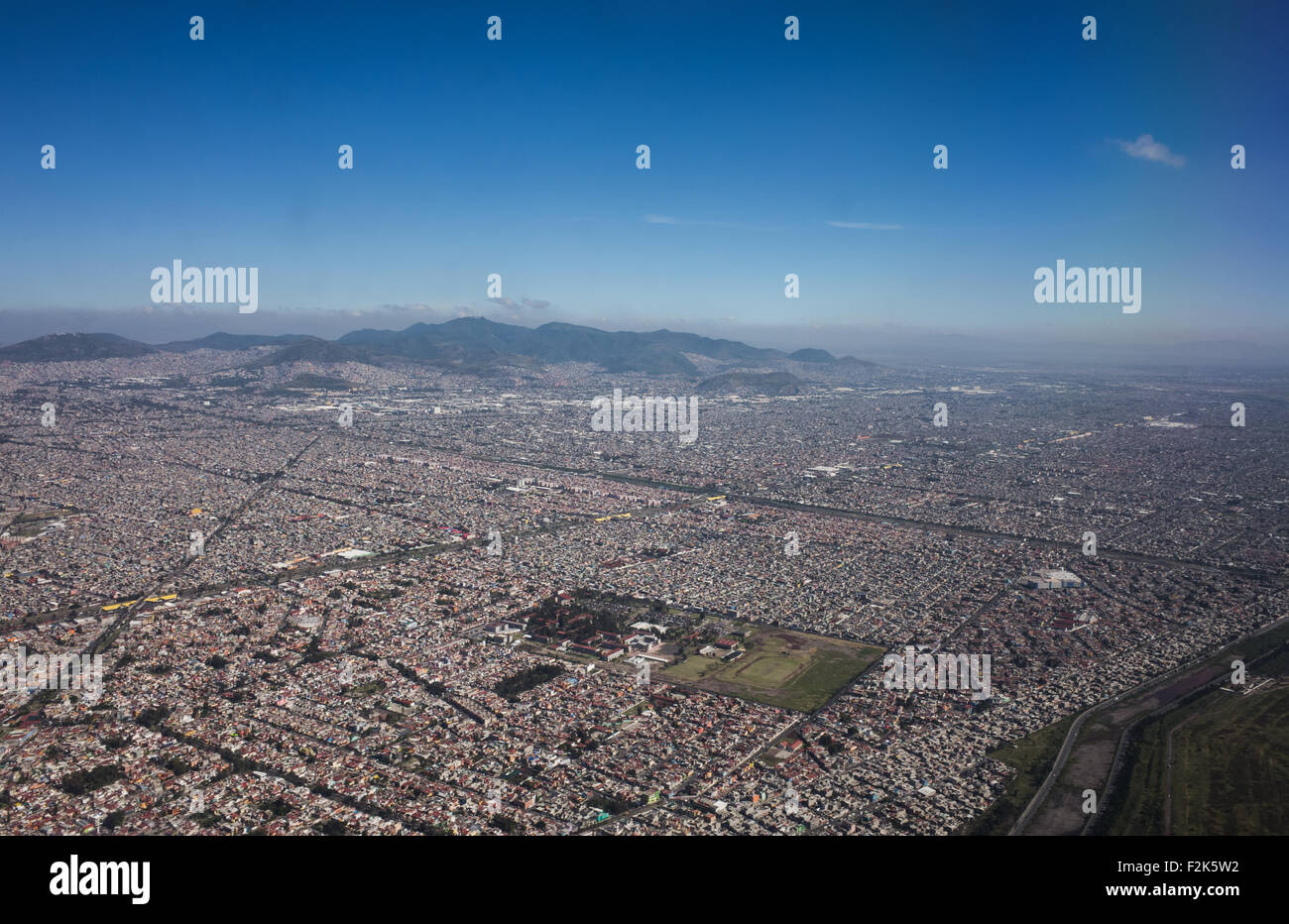 Mexico Aerial View Landscape // An aerial view of Mexico unfolds beneath the plane, revealing a diverse tapestry of landscapes. From rugged mountain ranges and sprawling deserts to lush forests and winding coastlines, this bird's-eye perspective showcases the country's rich geographical variety. Cities and rural areas alike punctuate the terrain, offering a stunning visual representation of Mexico's natural beauty and human development. Stock Photo