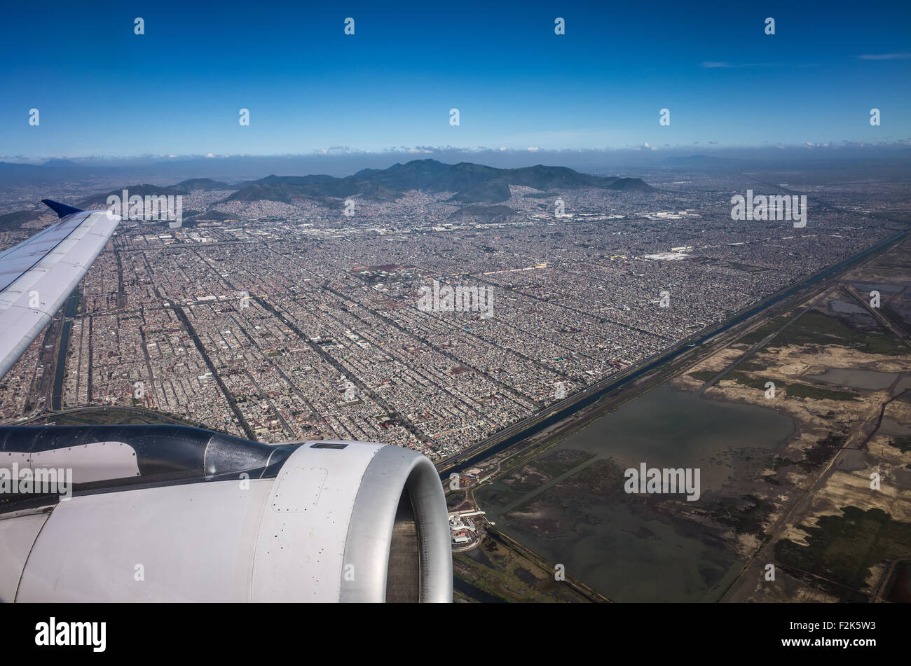 Mexico Aerial View Landscape Mexico // An aerial view of Mexico unfolds beneath the plane, revealing a diverse tapestry of landscapes. From rugged mountain ranges and sprawling deserts to lush forests and winding coastlines, this bird's-eye perspective showcases the country's rich geographical variety. Cities and rural areas alike punctuate the terrain, offering a stunning visual representation of Mexico's natural beauty and human development. Stock Photo