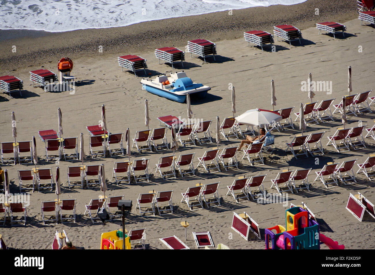 Rows of lawn chairs on beach, Riviera di Ponente at Spotorno, Liguria, Italy Stock Photo
