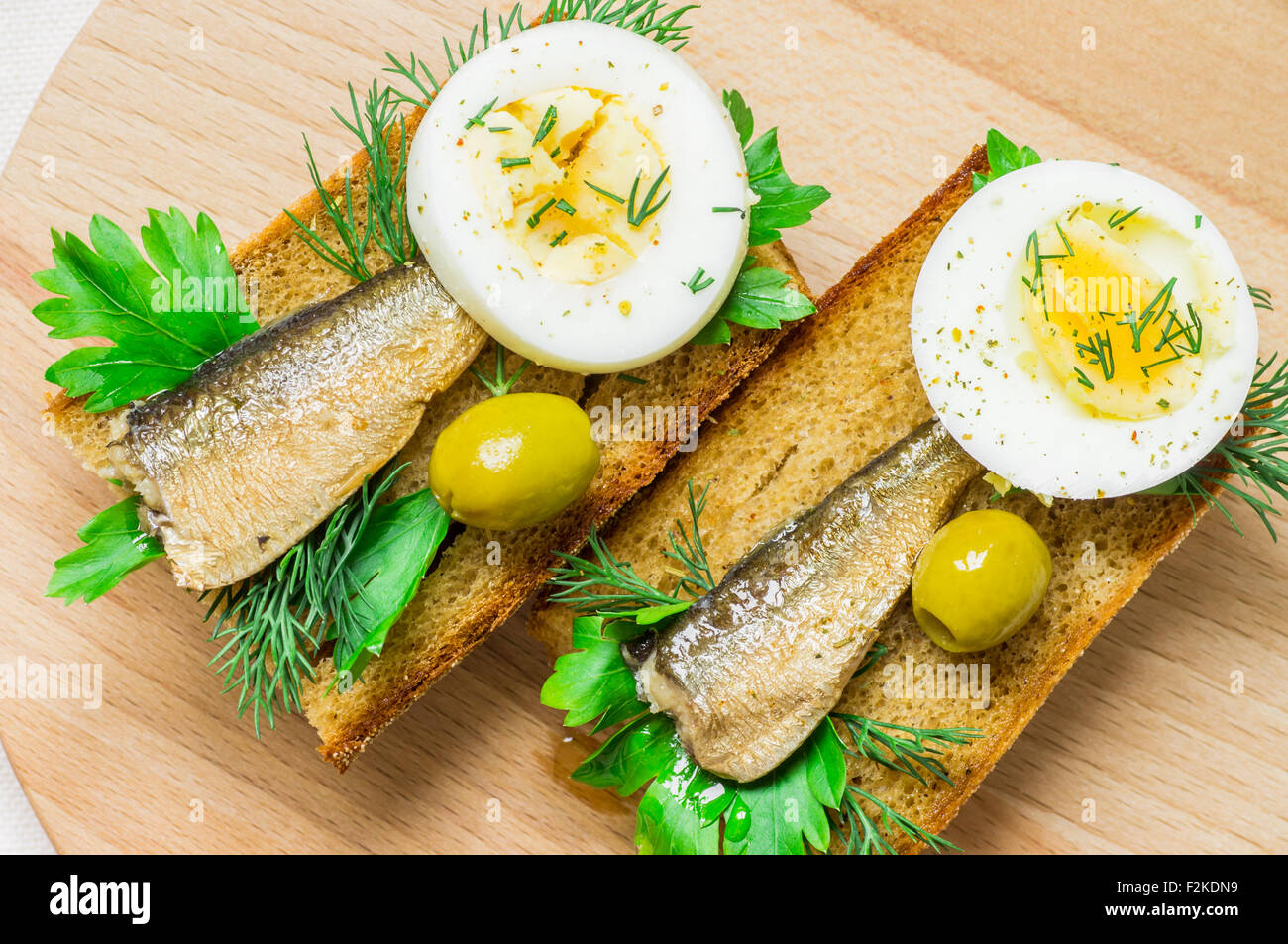Tasty sandwich sardines on toasted bread with green olives and egg