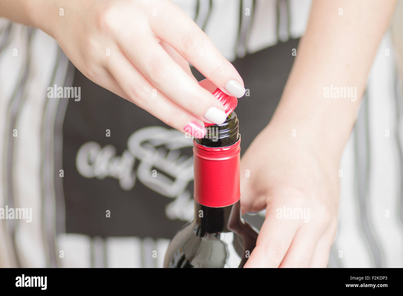 Female hand unscrews the screw cap red wine bottle Stock Photo