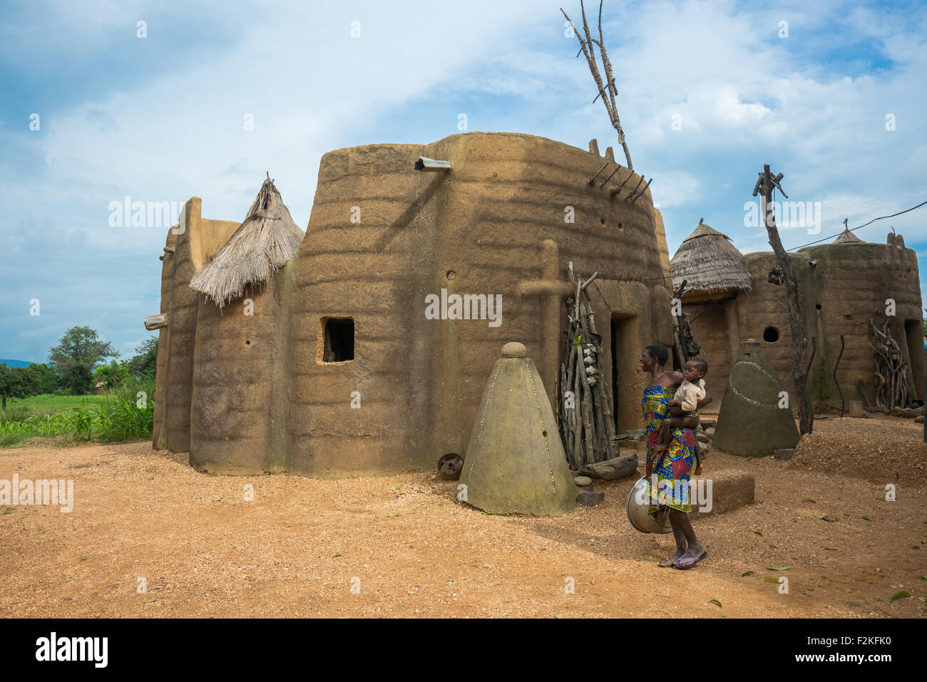 Benin, West Africa, Boukoumbé, mother and her baby in front of her traditional tata somba house with thatched roofs and granaries Stock Photo