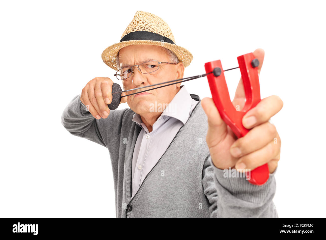 Angry senior gentleman aiming to shoot a rock with a slingshot isolated on white background Stock Photo